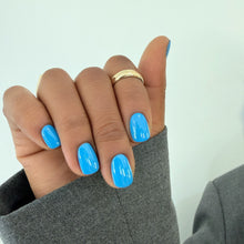 Charger l'image dans la galerie, Hand with blue nail polish wearing a gold ring on a light gray background