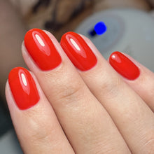 Charger l'image dans la galerie, Close-up of a hand with bright red nail polish on a blurred background