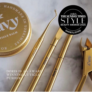 Gold cuticle pusher set with a jar labeled 'Doris' on a marble surface, featuring The Sunday Times Style Awards 2025.