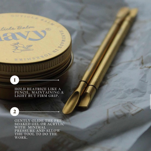Gold-colored tools with a container labeled 'Balm' on a textured surface