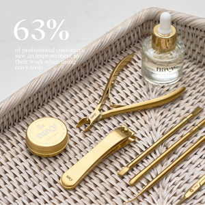 Set of gold beauty tools on a woven tray with a bottle labeled 'navy'.