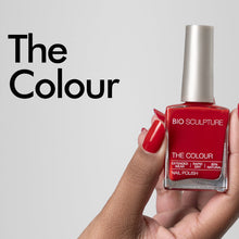Load image into Gallery viewer, A hand with red painted nails holds a bottle of red nail polish against a light gray background, with the text 'The Colour' printed on the left.