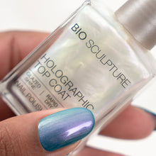 Charger l'image dans la galerie, A close-up of a hand holding a bottle of Bio Sculpture Holographic Top Coat nail polish, showing a blue-to-purple iridescent nail polish applied to the fingernail.