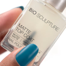 Load image into Gallery viewer, A close-up of a hand holding a bottle of Bio Sculpture Matte Top Coat nail polish. The fingernail is painted in the matte teal shade being advertised, and the bottle label reads 'MATTE TOP COAT' and 'NAIL POLISH'.