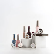 Load image into Gallery viewer, A collection of nail polish bottles and circular nail art pots arranged on white display blocks against a clean white background.